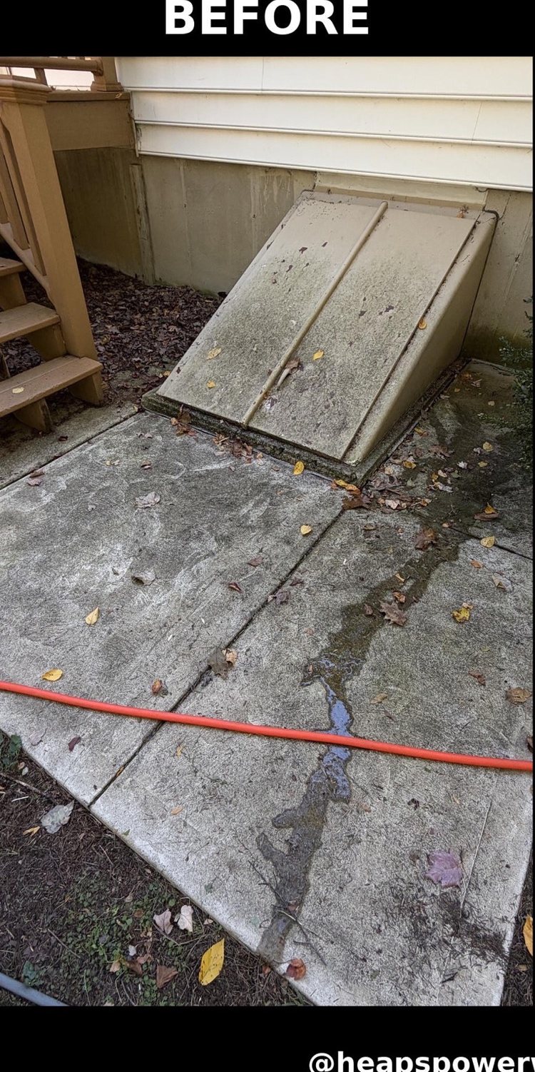 Stained concrete and a dirty cellar door before power washing